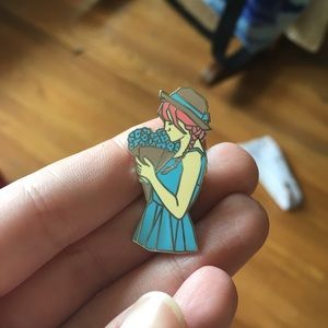 Blue enamel pin of girl holding flowers